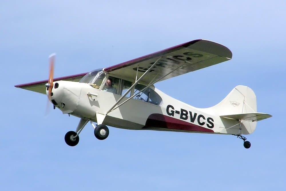 A yellow Aeronca 7AC Champion parked on grass, three-quarter front view