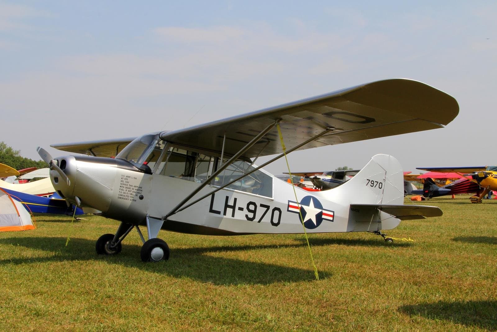 A restored olive-drab Aeronca L-16, registration N1143V, on a grass strip