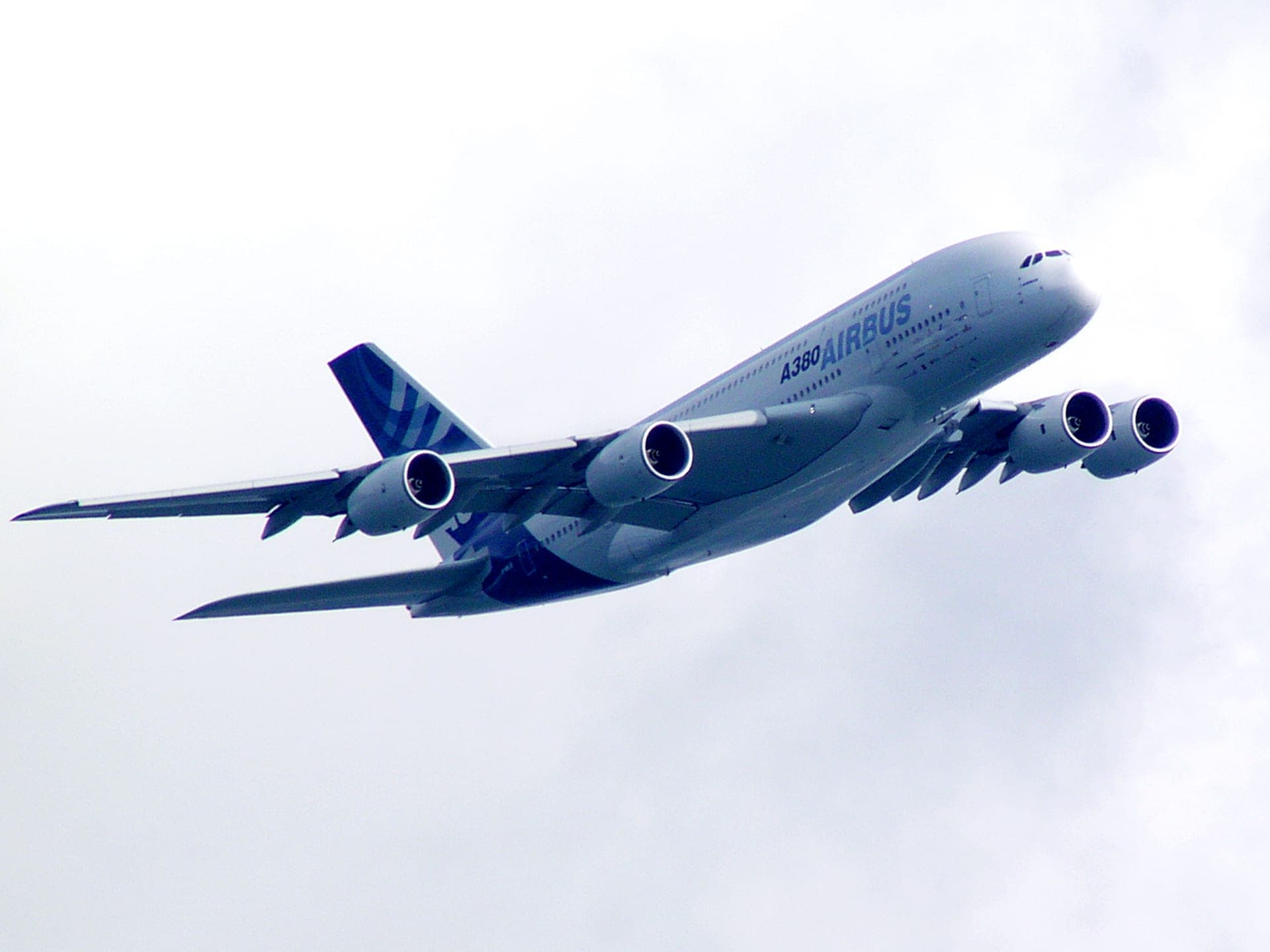 An Airbus A380 flying low over Victoria Harbour, Hong Kong, the city skyline visible beneath it