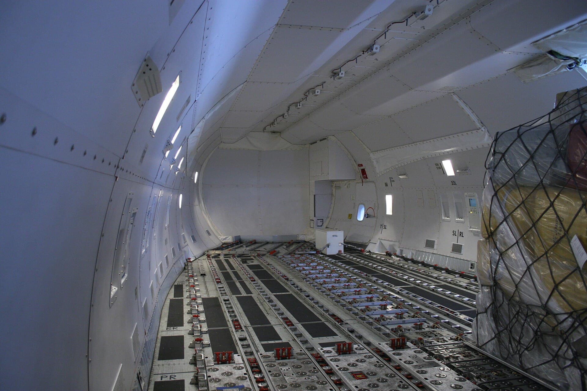 The empty main-deck hold of a Boeing 747-8F, its power-driven floor rollers and side guide rails running toward the nose