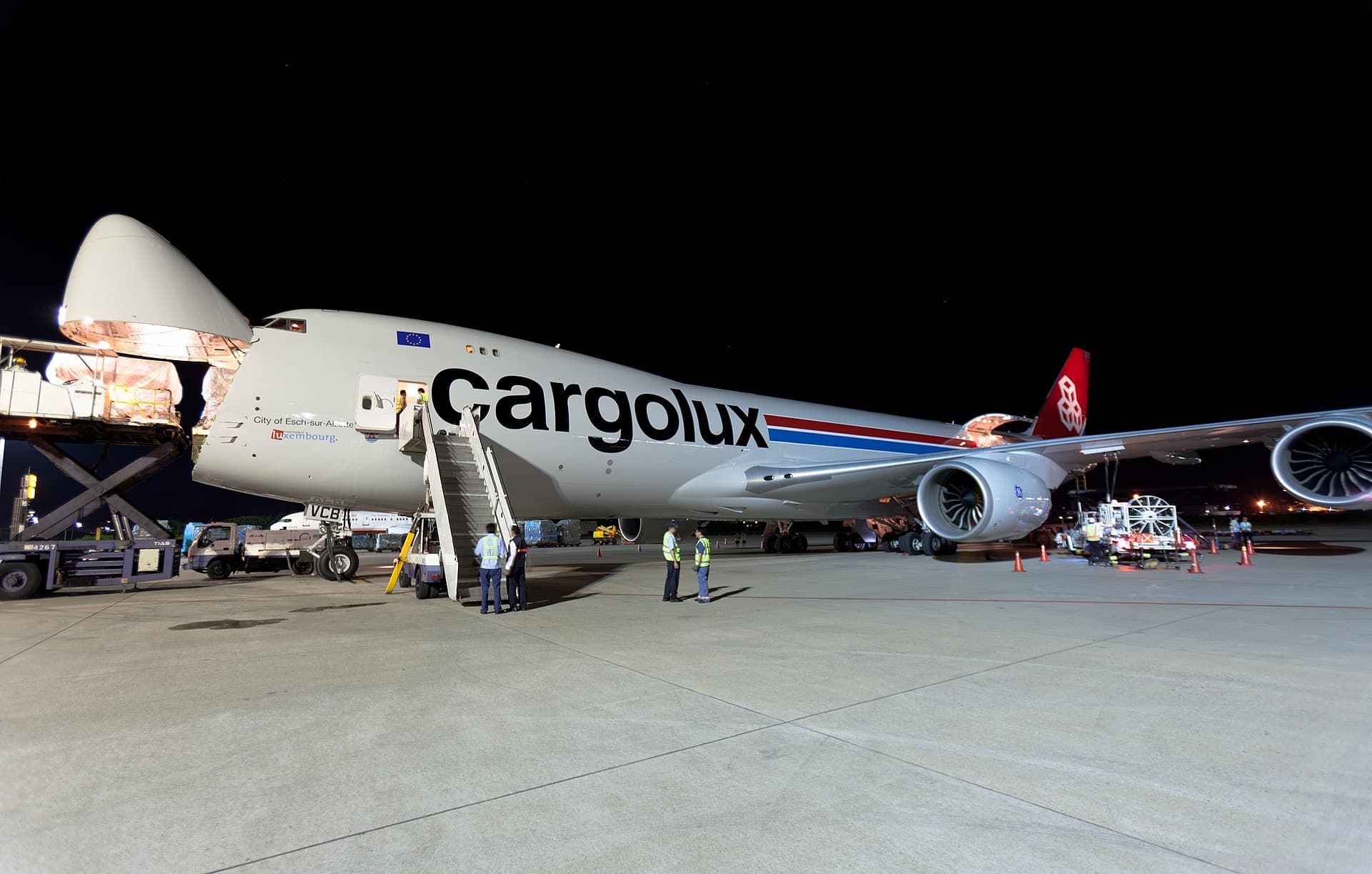 A Cargolux Boeing 747-8F on the ramp at night, its hinged nose raised open for cargo loading