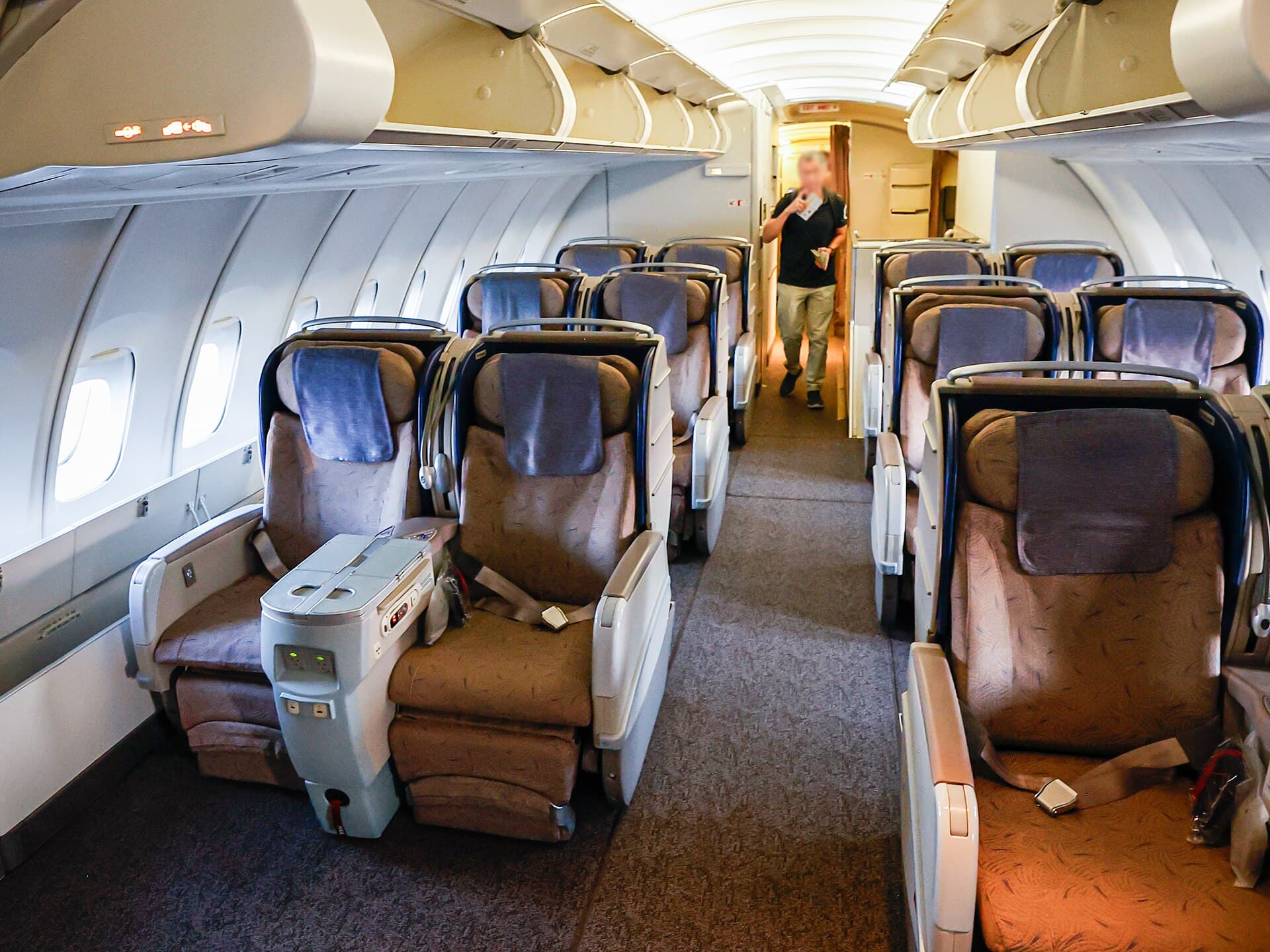 A ten-abreast economy cabin aboard an Asiana Boeing 747-400, rows of blue seats receding toward the rear bulkhead