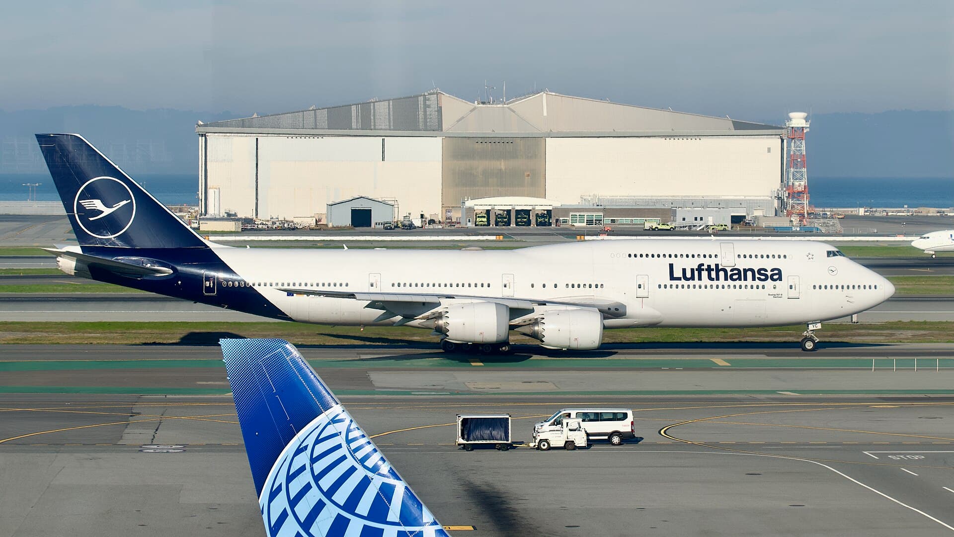 A Lufthansa Boeing 747-8 taxiing to depart San Francisco, its longer upper deck and raked wingtips visible in profile