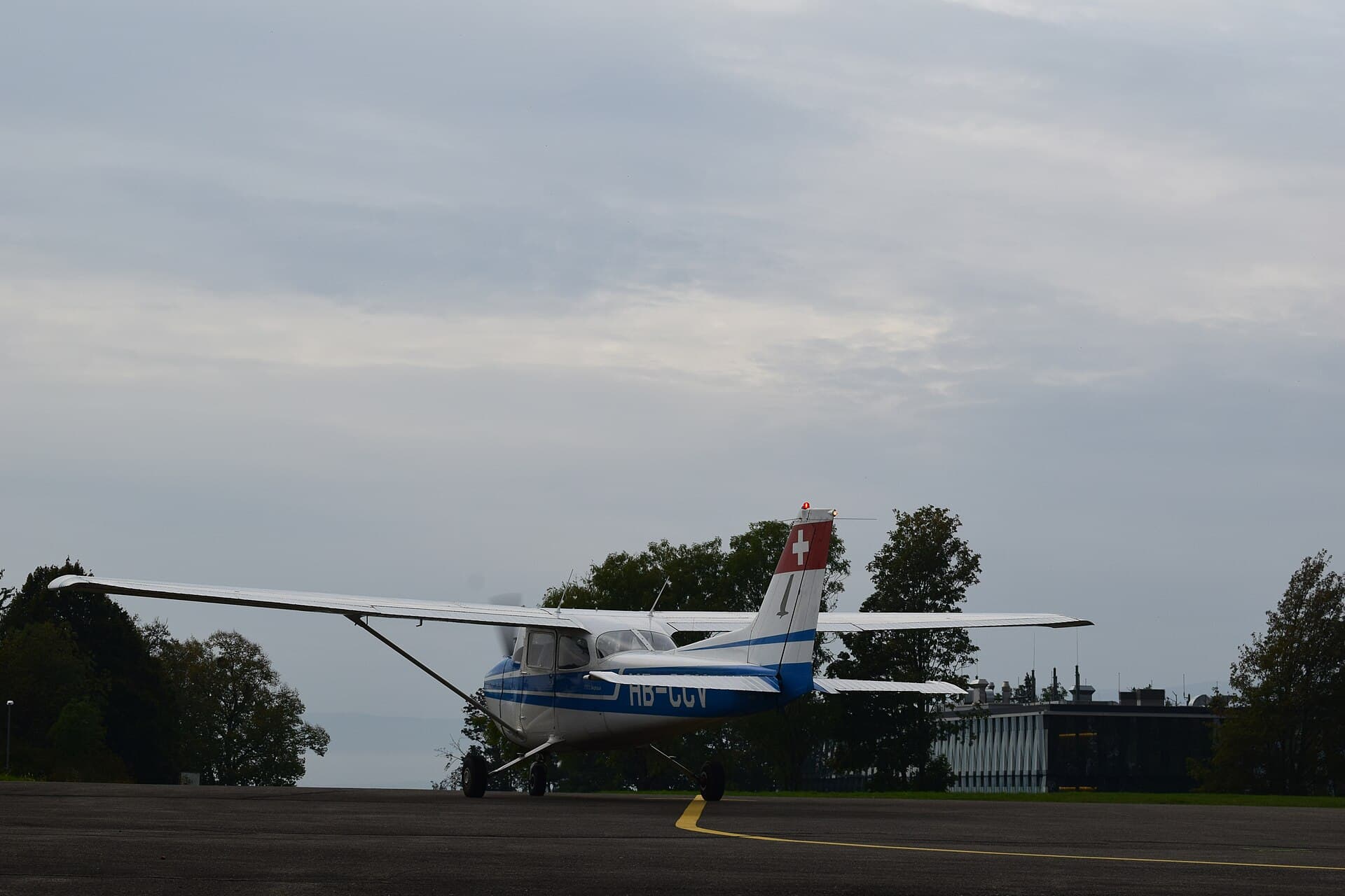 Un Cessna 172 immatriculé en Suisse en attente en bord de piste sous un ciel couvert