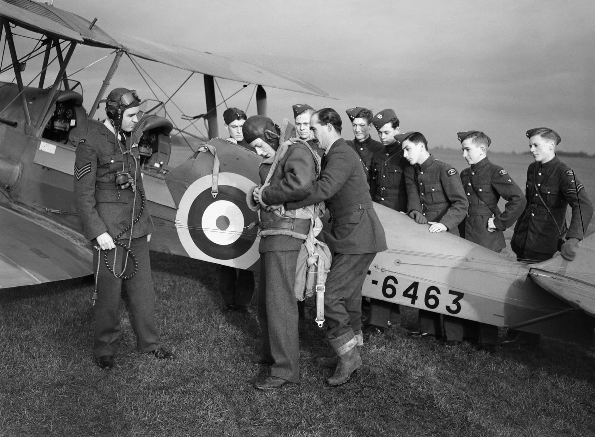 An Air Training Corps cadet secures his parachute before an air experience flight in a Tiger Moth at Biggin Hill, January 1942