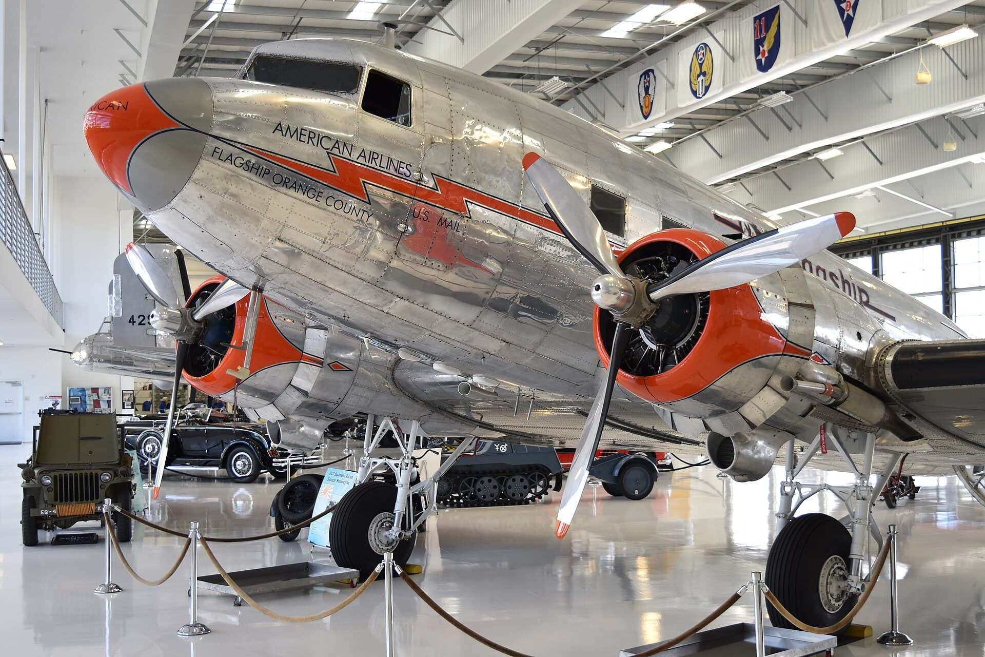 A restored Douglas DC-3/C-47, built in 1944 and now painted in American Airlines 'Flagship' livery, on static museum display beside period ground vehicles