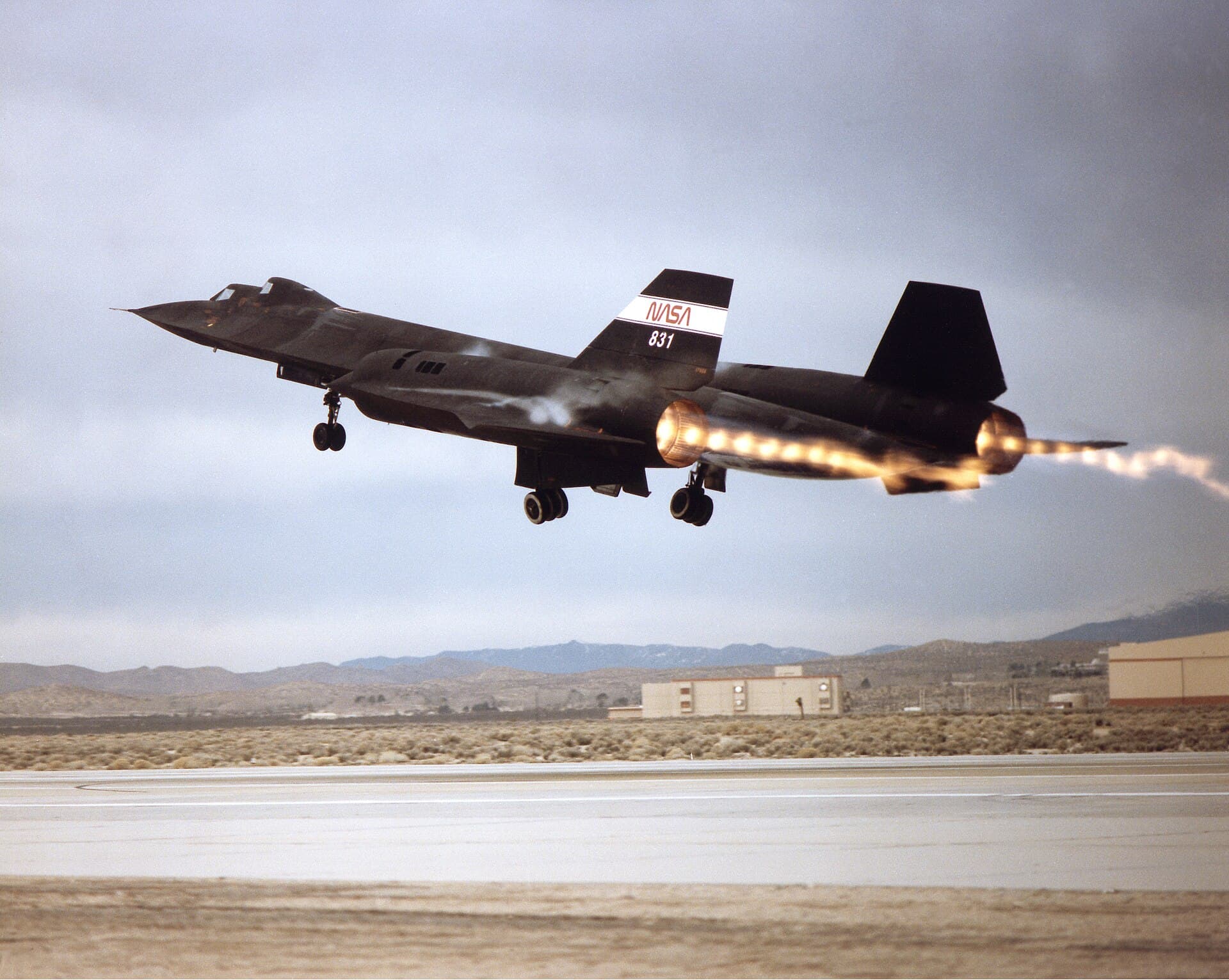 An SR-71 climbing away on takeoff with full afterburner, the exhaust plume showing bright shock diamonds