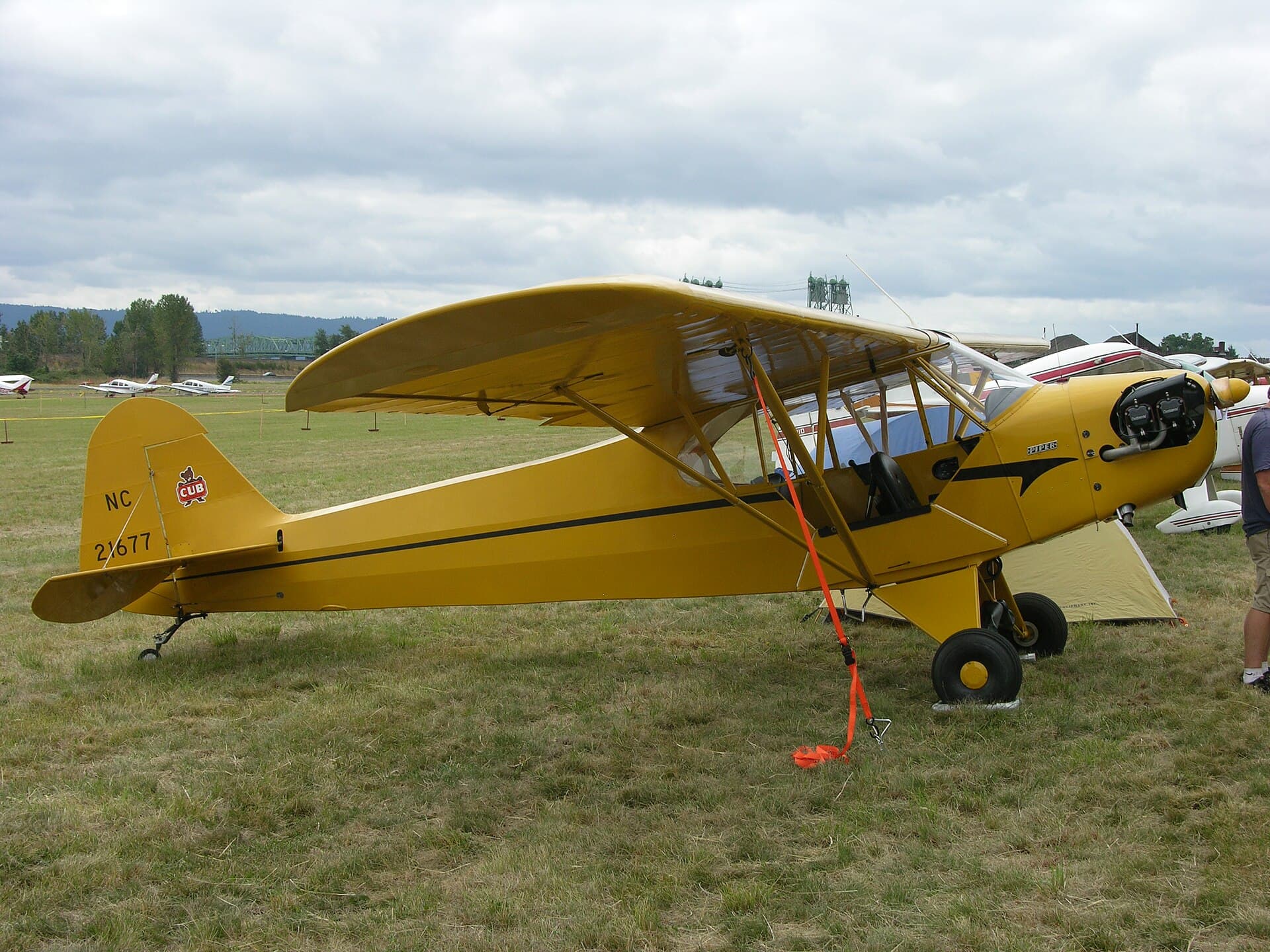 A 1938 Piper J3C-65 Cub, registration N21677, parked at an airshow