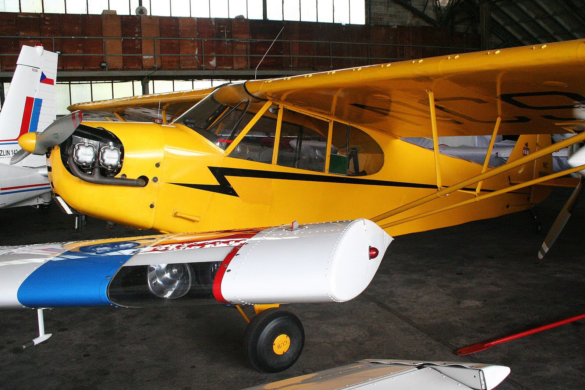 A yellow Piper J.3C-65 Cub, registration NC98689, parked on grass
