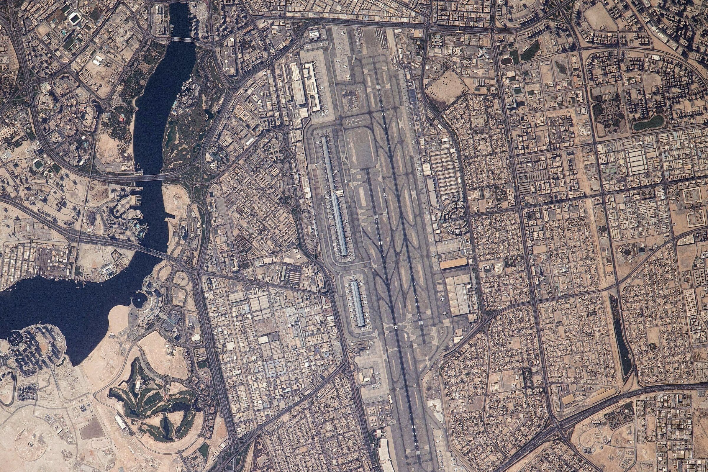 Dubai International seen straight down from the International Space Station in May 2021: two long parallel runways, the terminals alongside, and Dubai Creek to the west