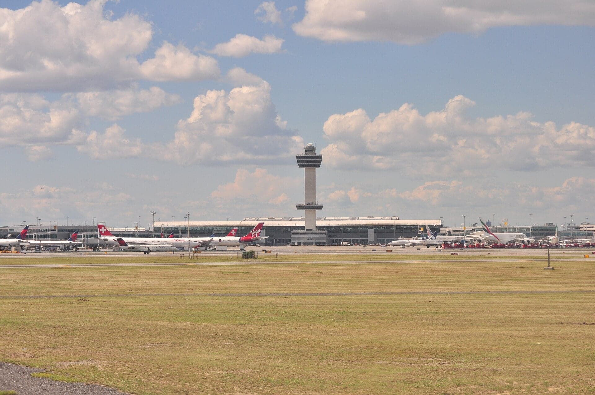 Terminal 2 and the 1994 control tower seen across the grass from a taxiway in 2013