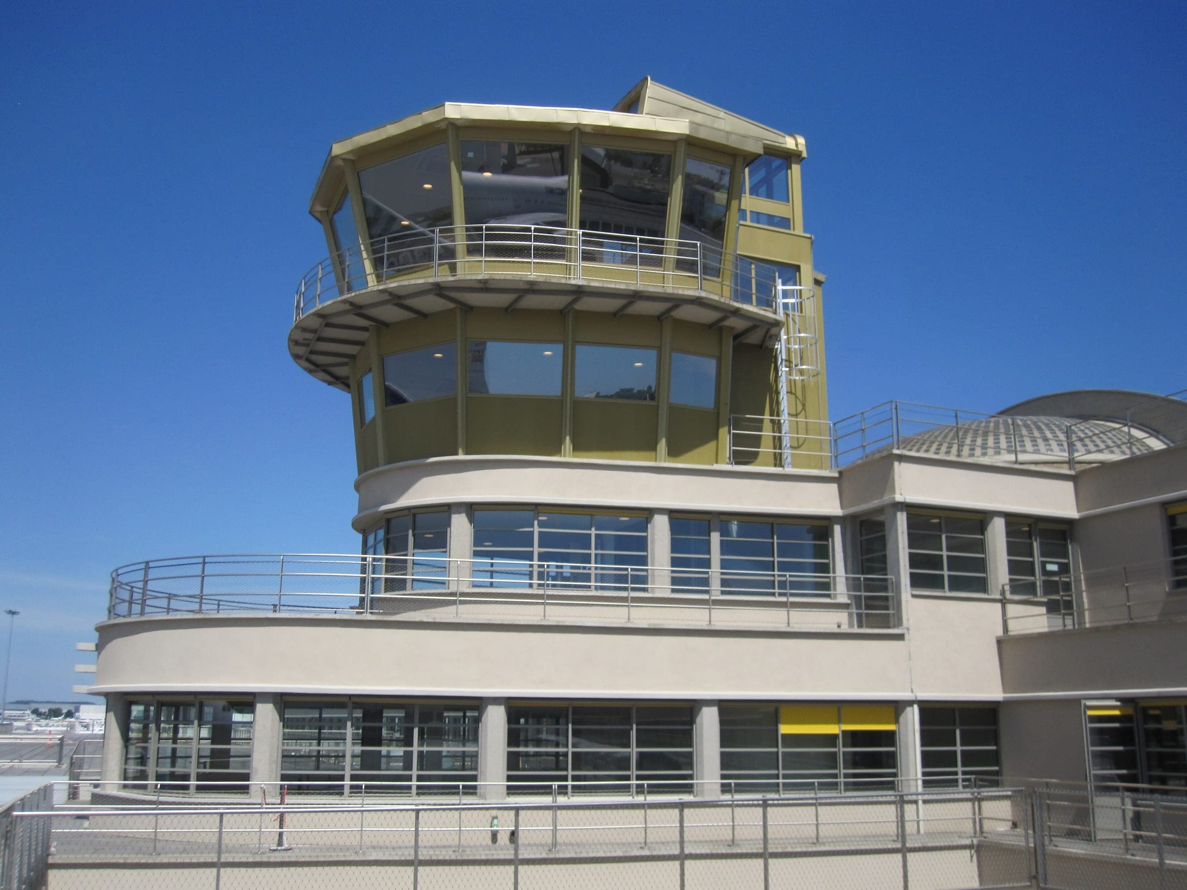 The old control tower rising above the curved terraces of the historic terminal, against a deep blue sky