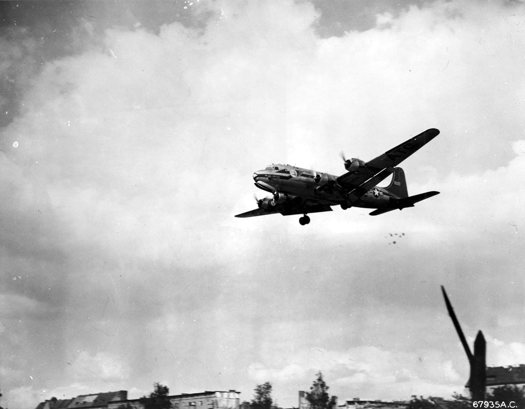 A C-54 on approach to Berlin trailing "Little Vittles" candy parachutes below its tail
