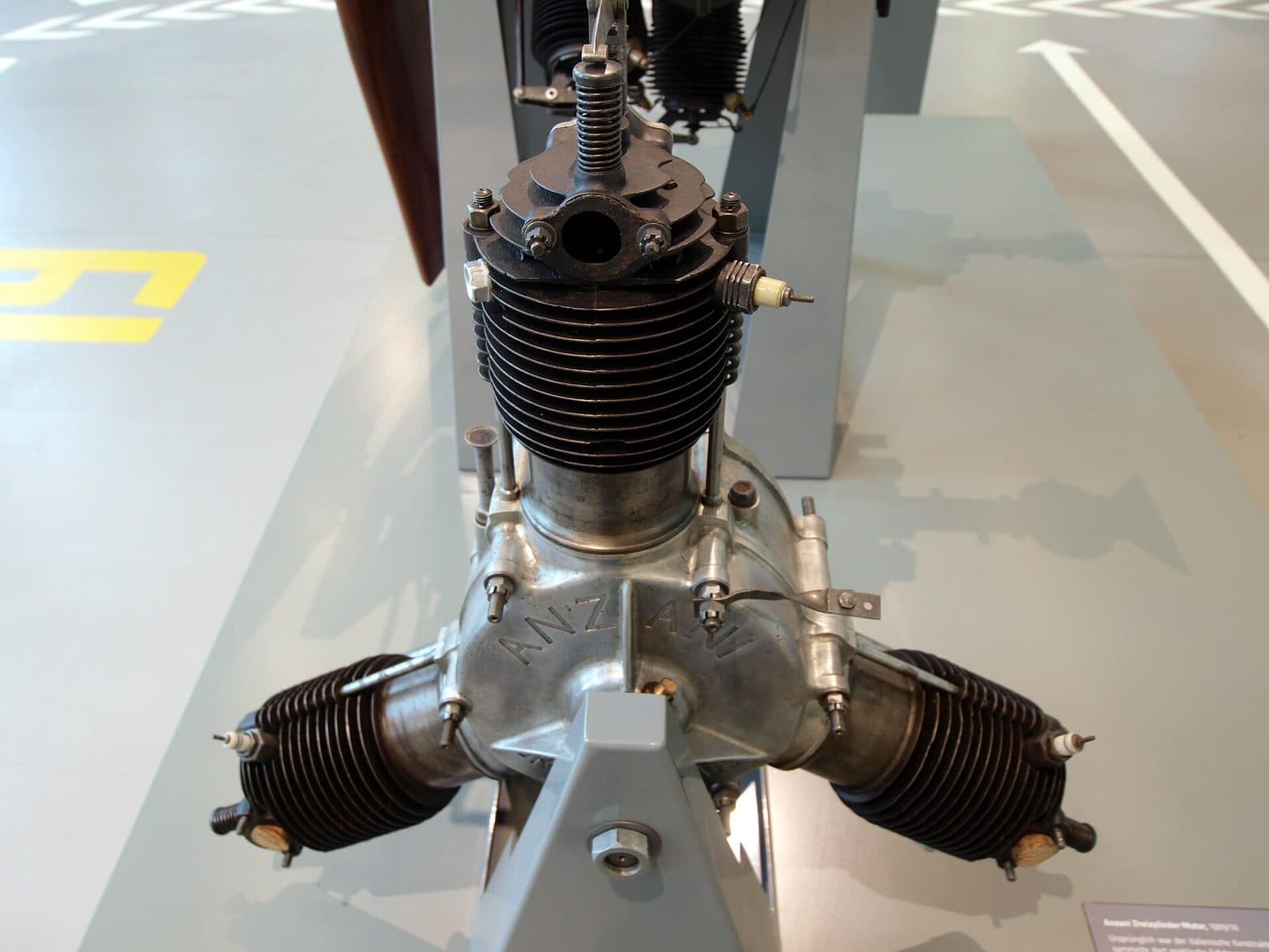 A 1909 Anzani three-cylinder aero engine on a museum stand, its cylinders splayed in a fan.