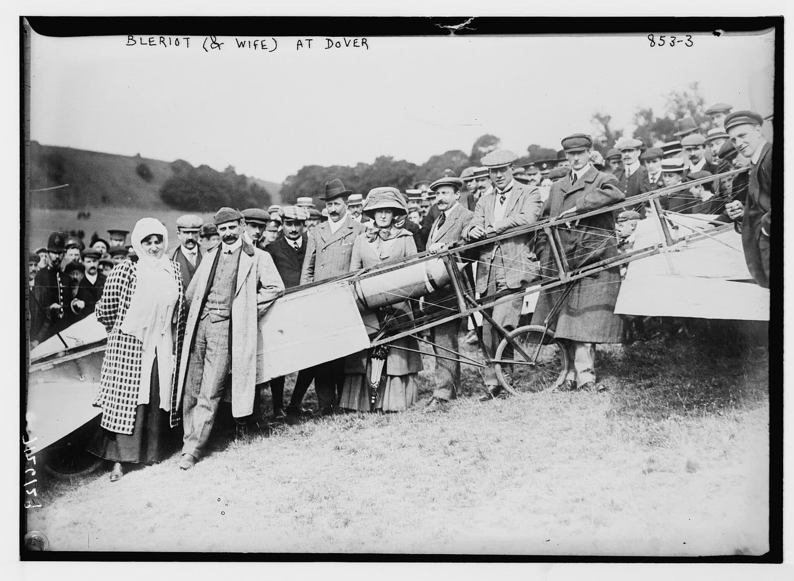 Louis and Alice Blériot with a crowd posing in front of the aeroplane on the field at Dover.