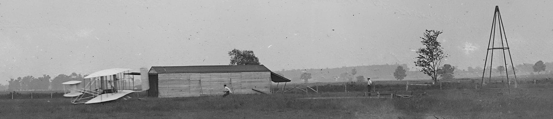 The start of the first flight of 1905 at Huffman Prairie: Orville at the controls beside the hangar, with the weight-and-derrick catapult that replaced the sea breeze.