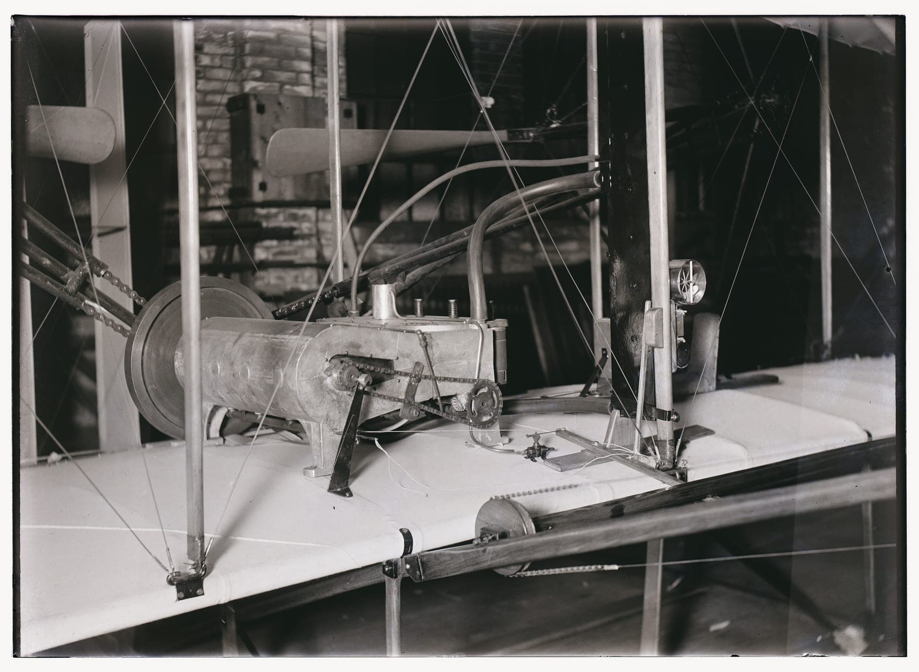 The central section of the 1903 Flyer photographed in the shop, showing the four-cylinder engine, the chain drives and the pilot's cradle.