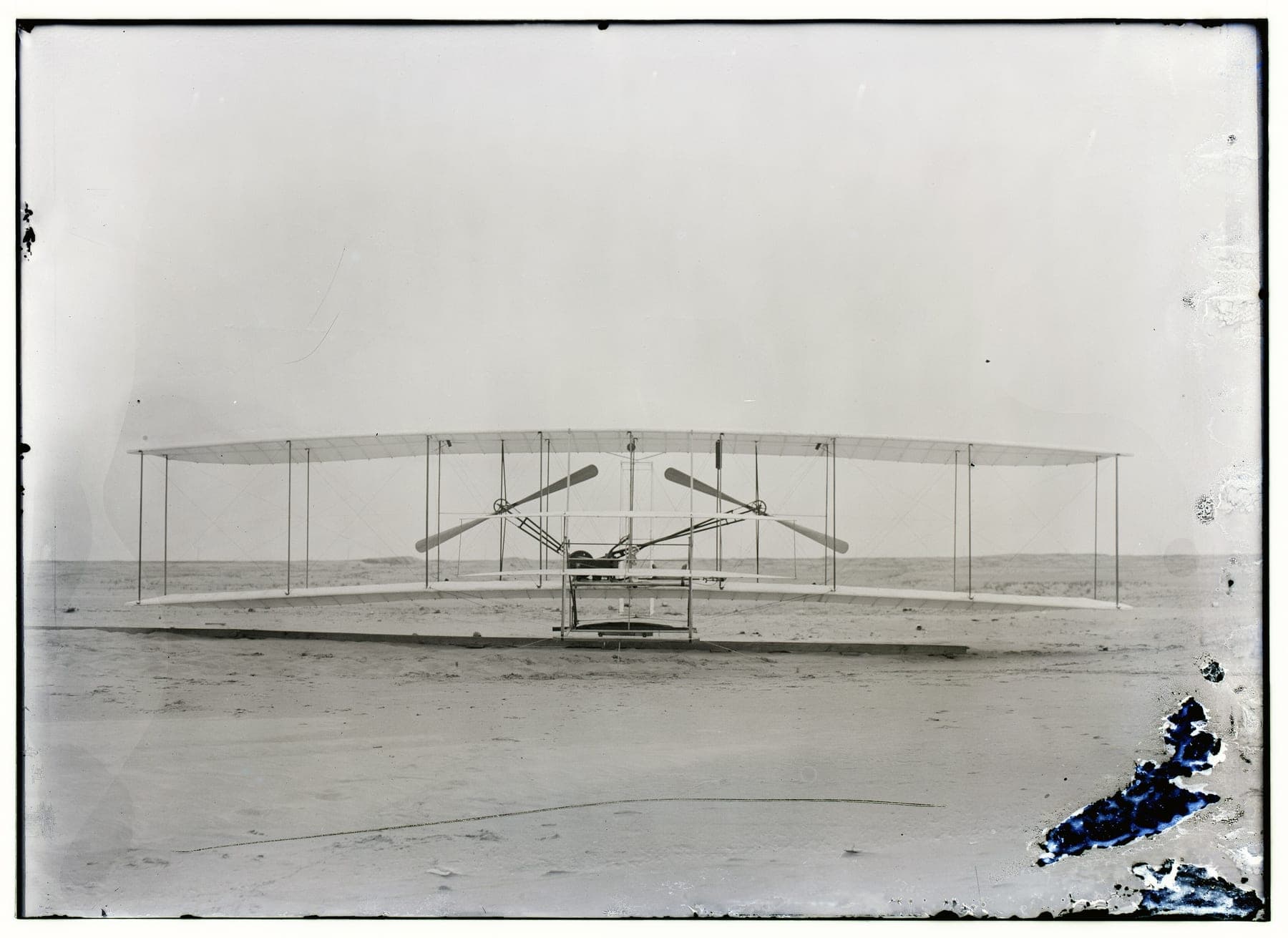 The 1903 Flyer photographed head-on, showing the twin pusher propellers, the chain tubes and the skids.