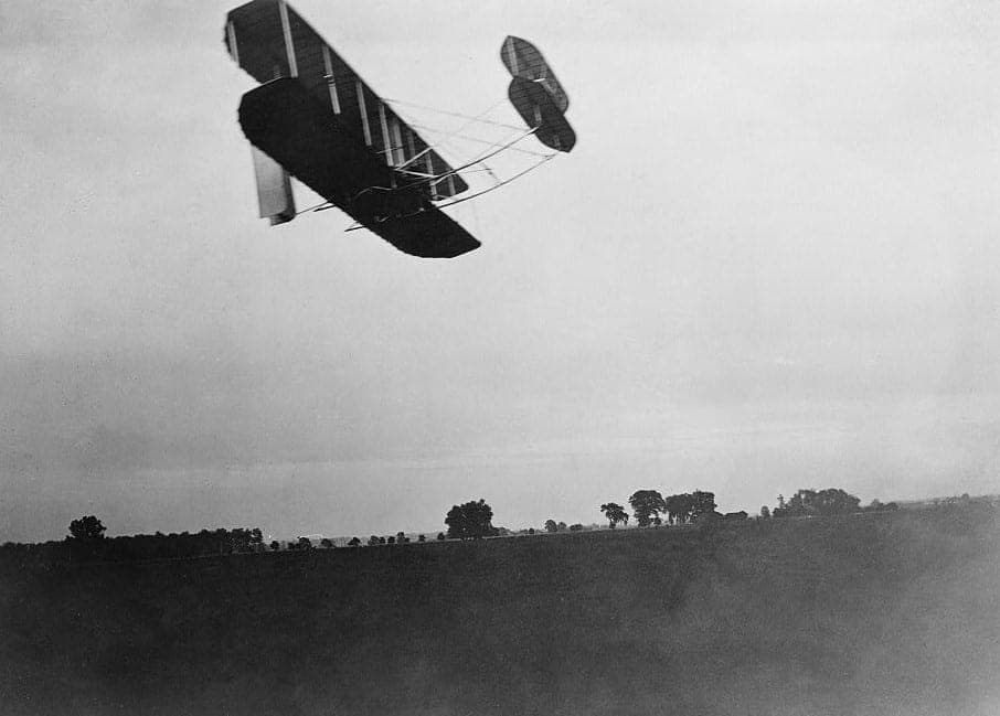 The 1905 Wright Flyer III in flight over Huffman Prairie, seen in side view.