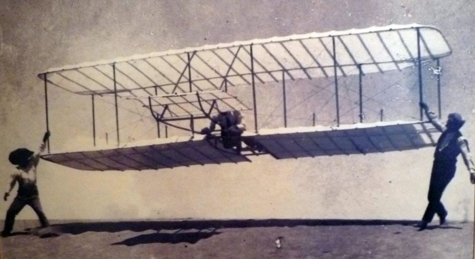 Wilbur Wright being launched in the 1901 glider by William and Dan Tate, one man at each wingtip.