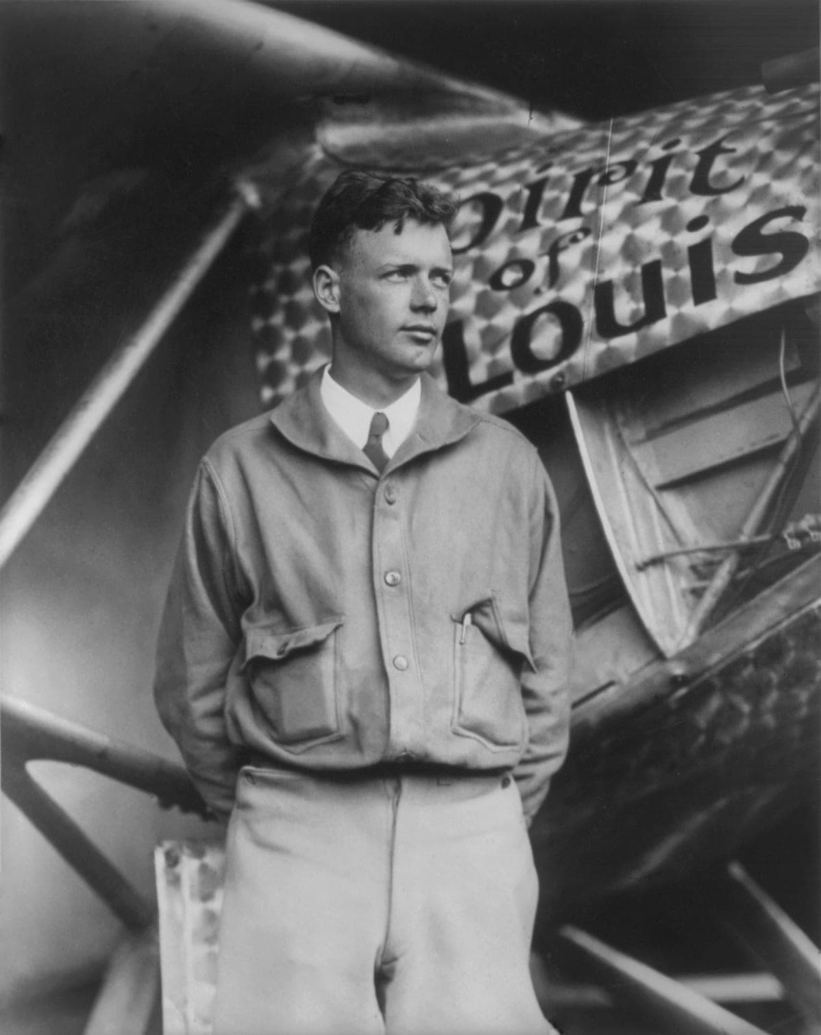 Portrait of Charles Lindbergh standing in front of the Spirit of St. Louis in 1927.