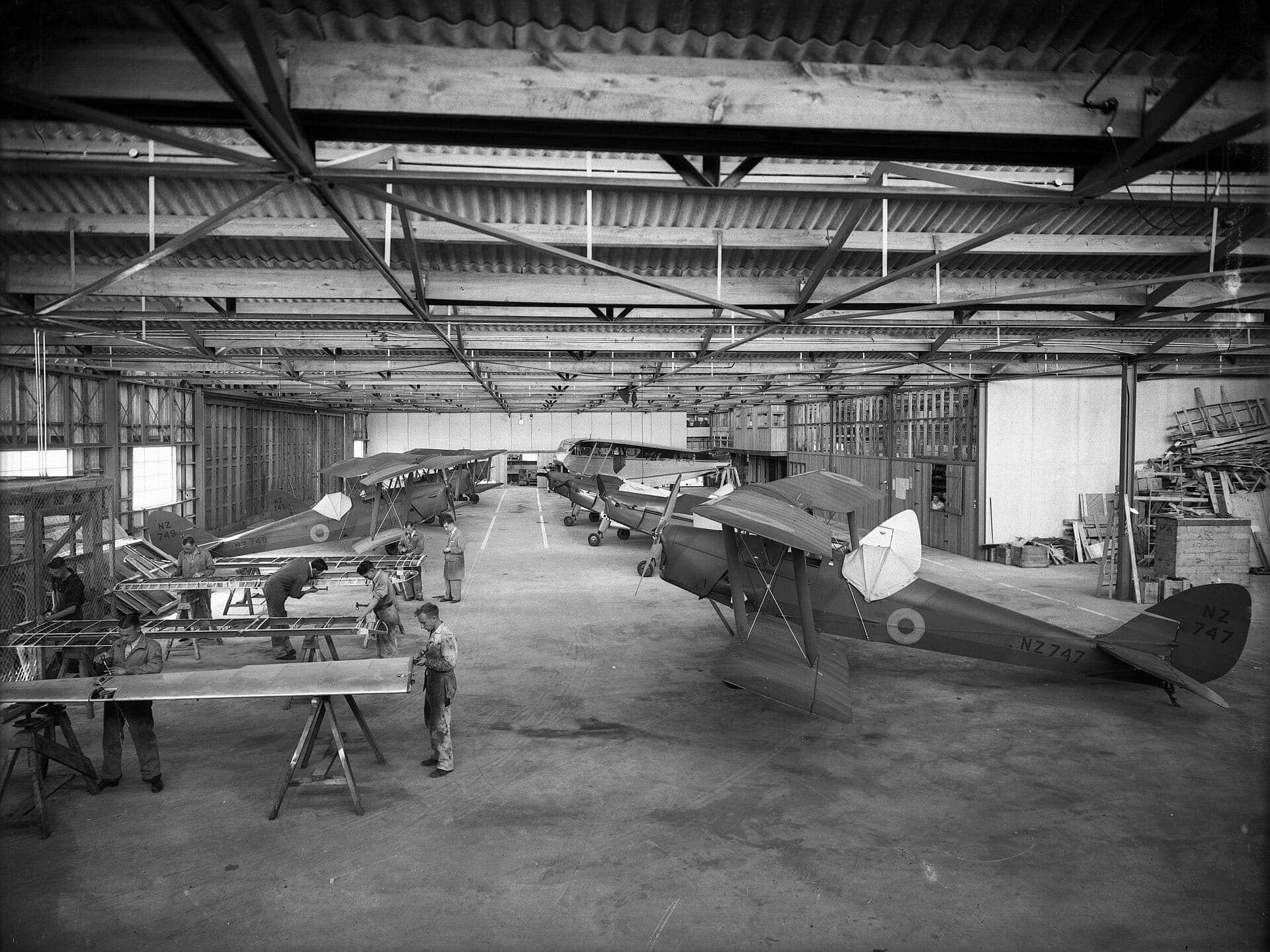 Workers building wings beside Tiger Moth trainers in RNZAF markings inside the de Havilland factory at Rongotai, Wellington