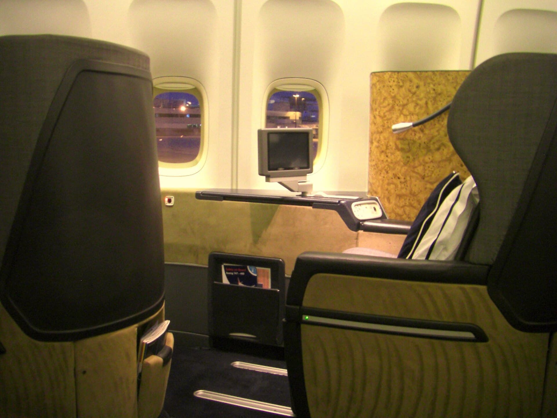 A British Airways First cabin on a 747, wide leather seats spaced well apart beneath dimmed reading lights
