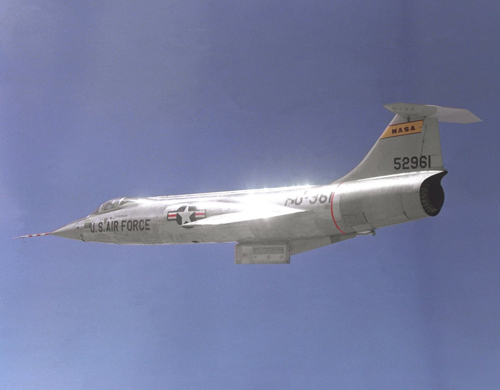 A NASA JF-104A Starfighter with its short, thin wings and a test fixture mounted under the fuselage